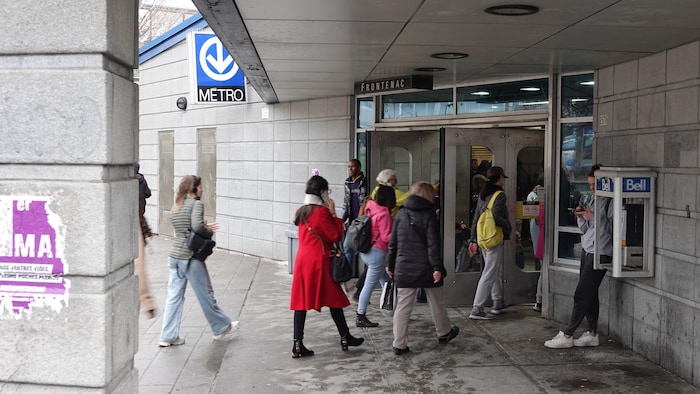 Des gens franchissent l'entrée de la station Frontenac du métro de Montréal.