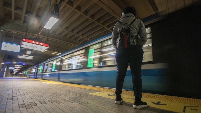 Une personne debout regarde passer un métro.