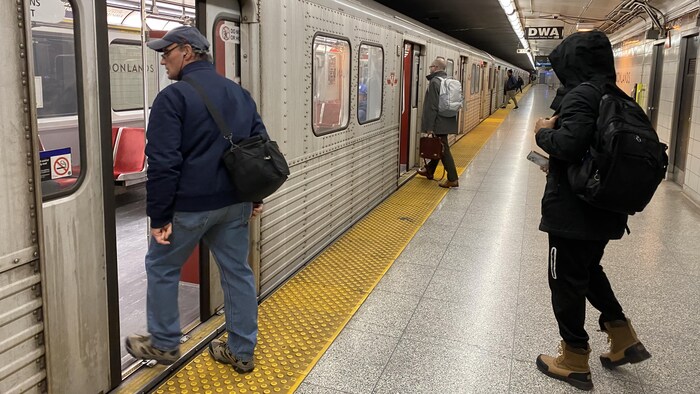 Des usagers montent à bord d'une rame de métro.