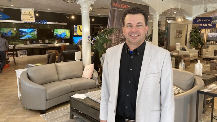 François Émond est dans son magasin, devant des meubles.