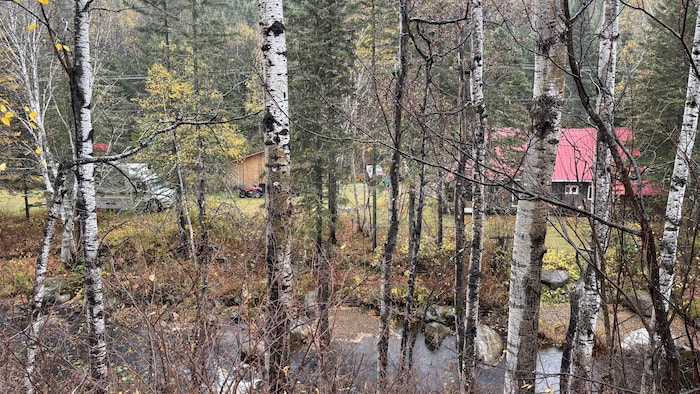 Un véhicule est stationné près d'une maison dans les bois.