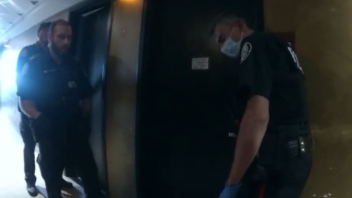 Des policiers tentent de parlementer devant une porte close.