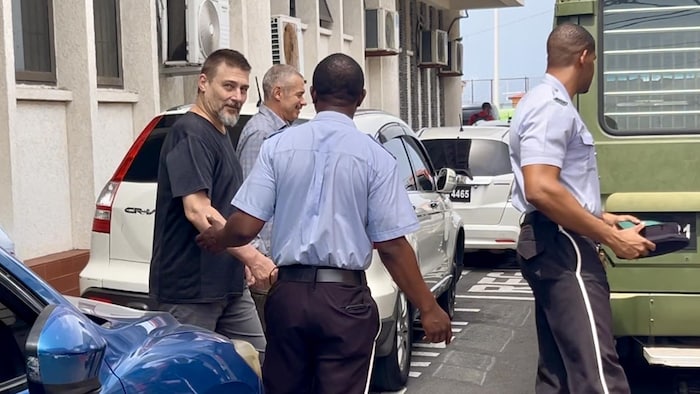 Deux hommes marchent escortés par des policiers.