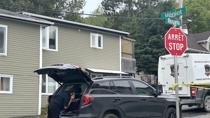 Une personne qui travaille pour les services de police, devant la résidence où s'est produit le meurtre. 