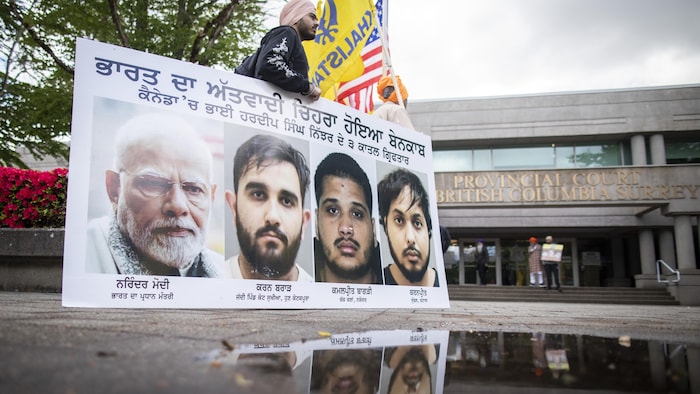 Un partisan tenant une pancarte la photo du premier ministre indien, Narendra Modi, et celles des quatre accusés.