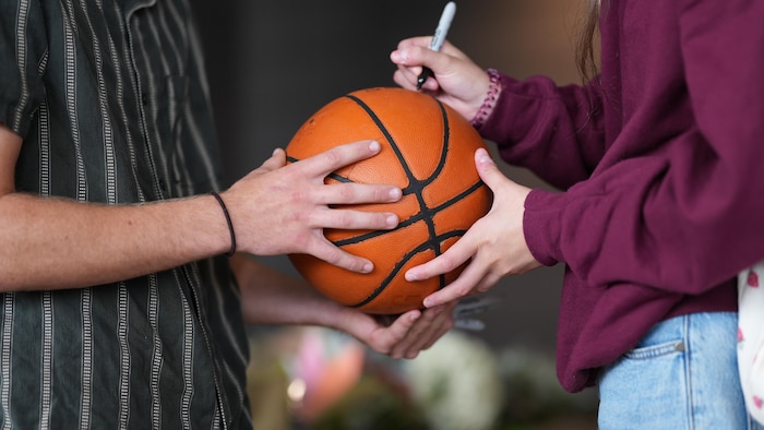 Des jeunes qui signent un ballon.