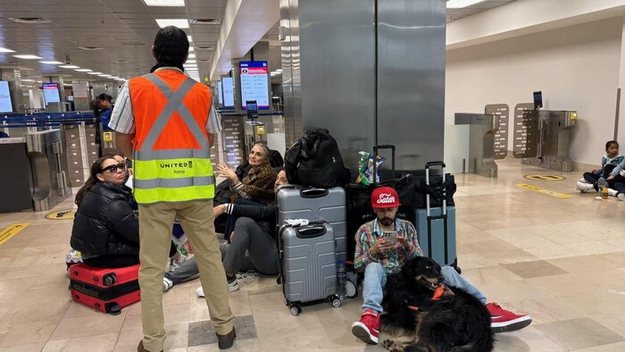 Les passagers attendent des informations à l'intérieur de l'aéroport de Puerto Vallarta avec leurs valises.