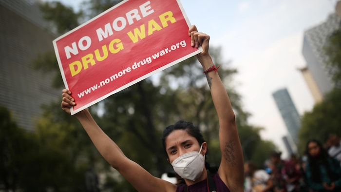 Une femme portant une pancarte sur laquelle est écrit en anglais No more drug war (plus de guerre des drogues).