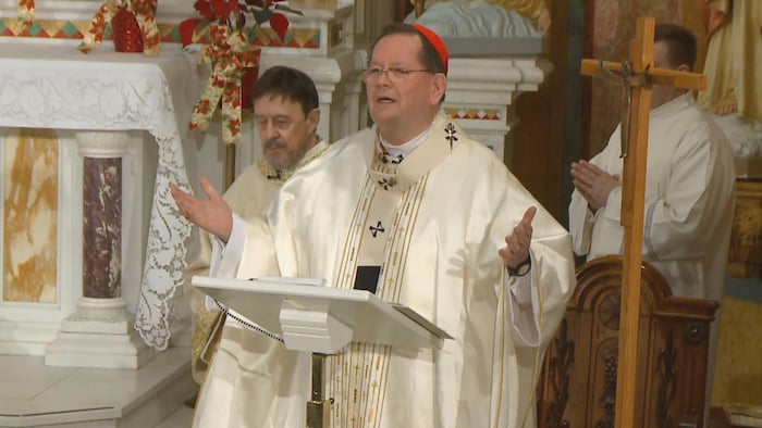 Un cardinal ouvre les bras au-dessus de l'autel d'une église.
