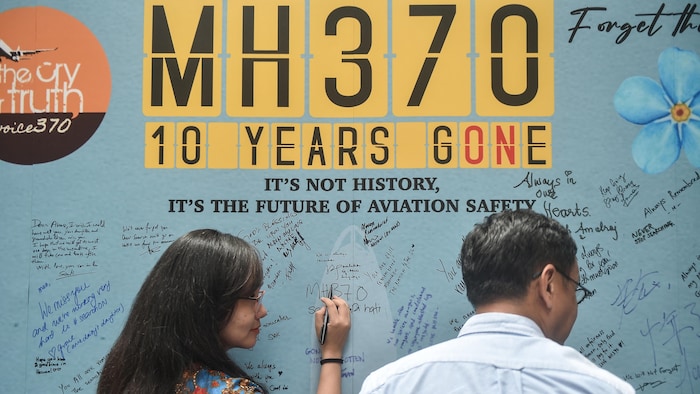 Une femme écrit un message sur un panneau commémoratif lors d'un événement organisé par les proches des passagers pour marquer le 10e anniversaire de la disparition du vol MH370.