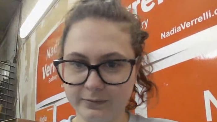 Mia Vallière devant des pancartes pour Nadia Verrelli.