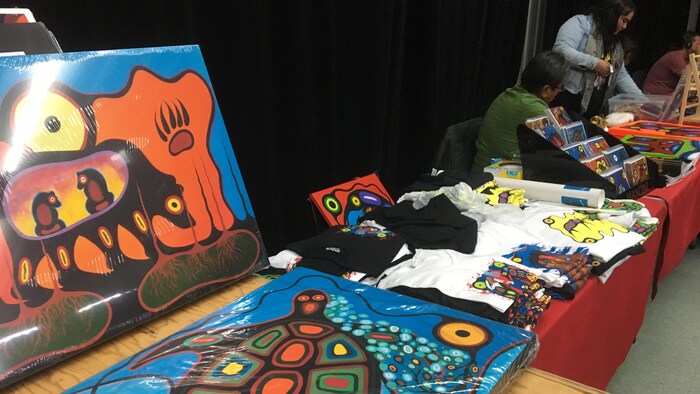 Des peintures et des objets décorés d'inspiration autochtone sont disposés sur des tables. 