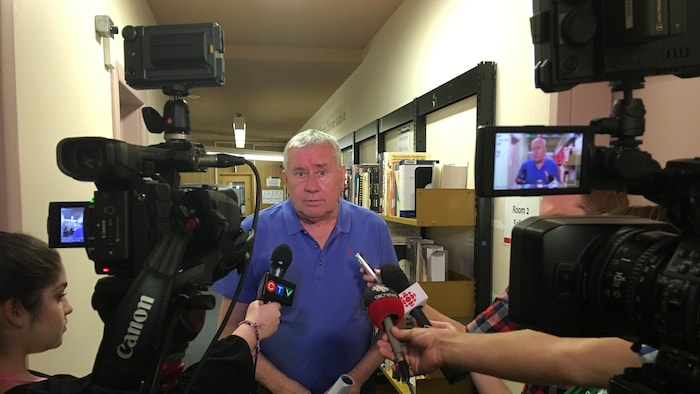 Un homme en entrevue avec des journalistes.