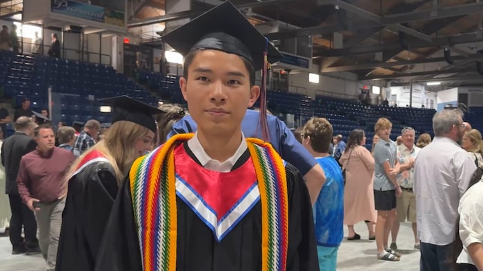 Michael Liu avec une ceinture fléchée et des habits de graduation.