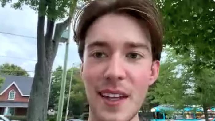 Un homme sourit devant une caméra.