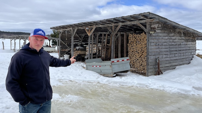 Michaël Plumier pointe un hangar avec un toit et des murs abritant du bois.