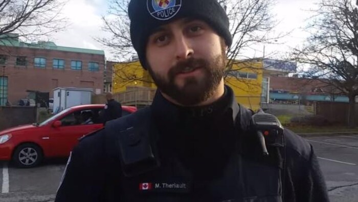 Michael Theriault en uniforme de la police à l'extérieur.