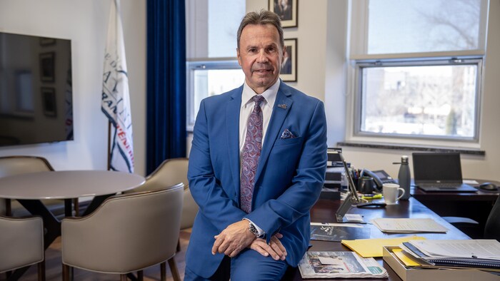 Michel Angers assis sur son bureau.