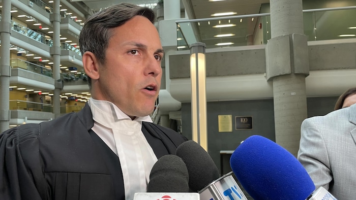 Un homme devant les micros des journalistes.