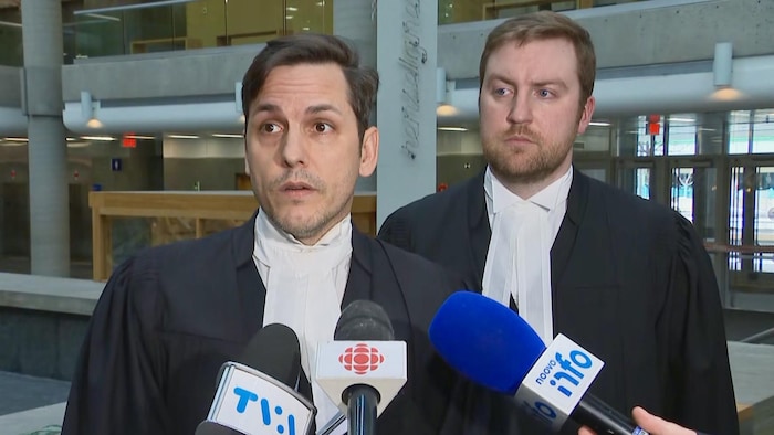 Deux hommes, en toge, s'adressent aux journalistes.