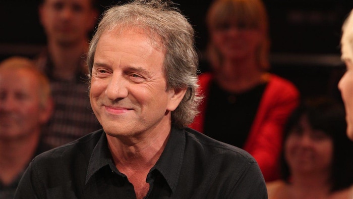 Michel Côté souriant sur un plateau télé.