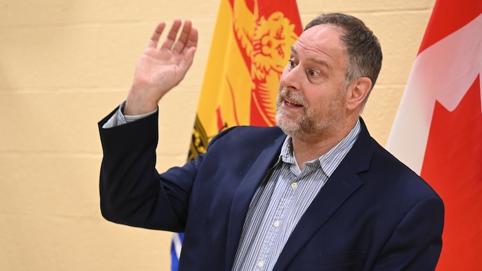 Une personne devant des drapeaux du Nouveau-Brunswick et du Canada.