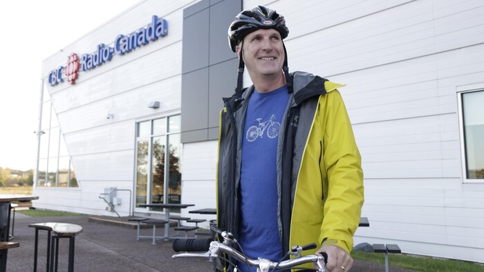 Un homme debout à côté d'un vélo et portant un casque protecteur. 