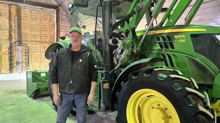 Michel Dignard photographié à côté d'un tracteur.
