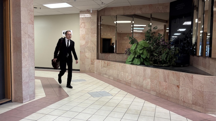 Michel Leblanc Desneiges marche dans un corridor.