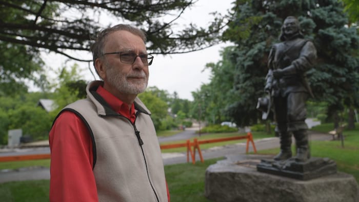 Michel Prévost en entrevue, à côté de la statue de Samuel de Champlain.