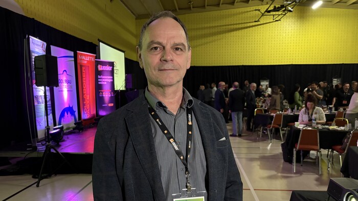 Un homme pose dans une salle de conférence.