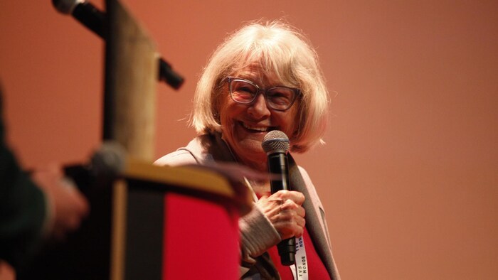 Un protrait de Micheline Lanctot souriante derrière un micro.