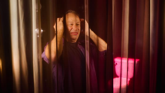 Un homme avec du rouge à lèvres se regarde dans un miroir.