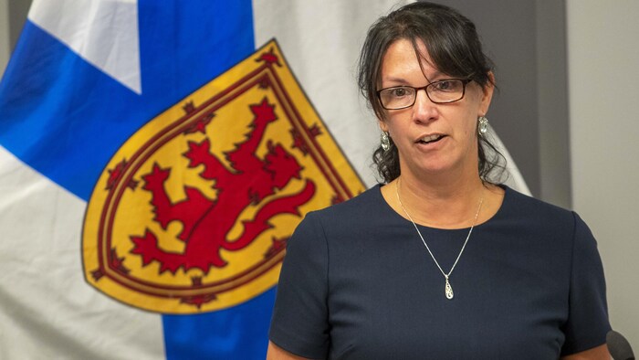Michelle Thompson assise en conférence de presse devant un drapeau de la Nouvelle-Écosse.