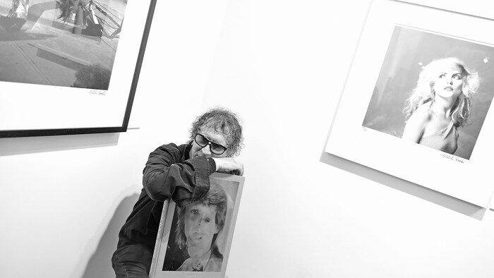 L'homme pose avec des photos. Il est assis.
