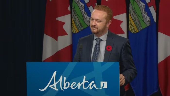Mickey Amery, ministre de la Justice de l'Alberta, se tient devant un lutrin.