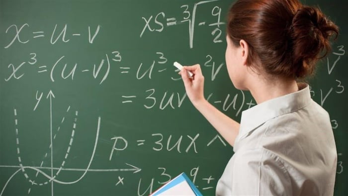 Une enseignante écrit au tableau