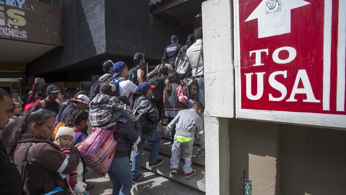 Des migrants font la file devant un immeuble.