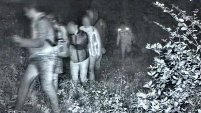 Une photo floue de migrants dans la forêt.