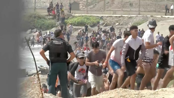 Des migrants marchent aux côtés d'un membre de la Guardia Civil de l'USECIC après avoir traversé à la nage la frontière de Ceuta, en Espagne, depuis le côté marocain pour atteindre la barrière frontalière, à Ceuta, en Espagne, le 30 juillet 2026.