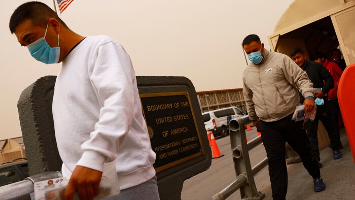 Des hommes sortent d'un pont frontalier.