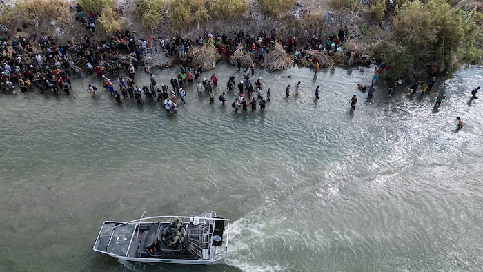 Des migrants dans l'eau, près d'un bateau.