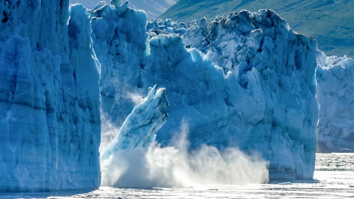Des morceaux d'un glacier se détachent et tombent dans la mer. 