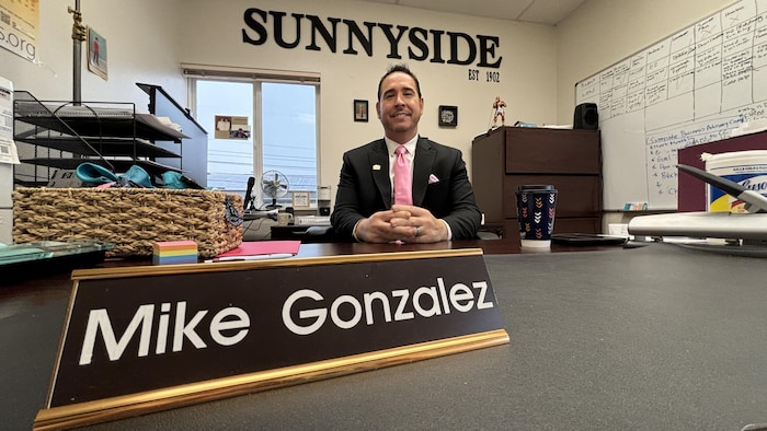 Un homme est assis à son bureau les mains croisées