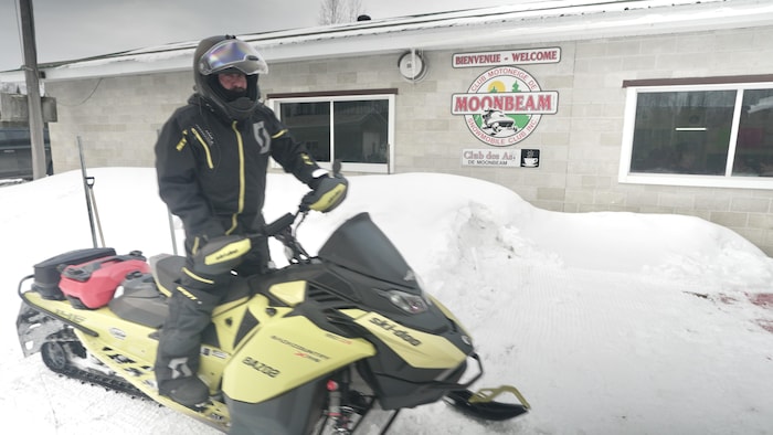Un homme sur sa motoneige devant le Club des As.