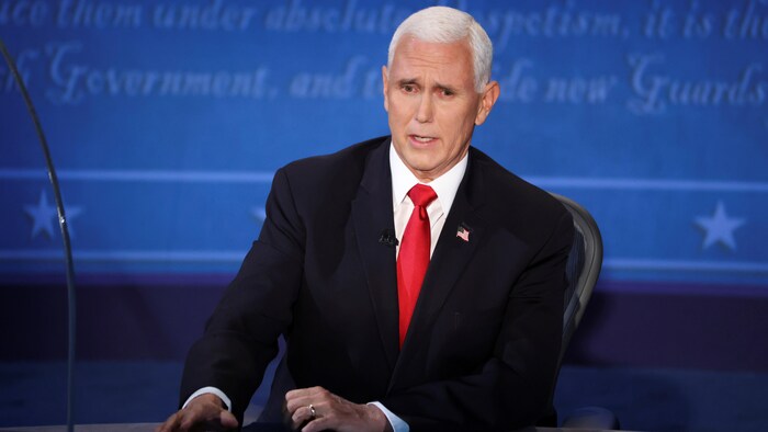 Mike Pence parle assis derrière un bureau lors d'un débat.