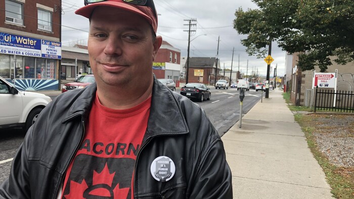 Un homme dans la rue fait un sourire à la caméra dans une rue de Hamilton.