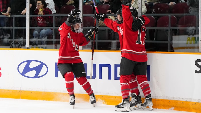 Trois joueuses d'Ottawa célèbrent après un but pendant un match de la LPHF.