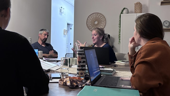Quatre personnes discutent autour d'une table.