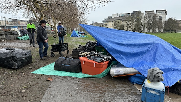 Des personnes autour d'une tente et de sacs de toutes sortes, dans un parc, à Victoria.